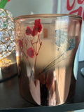 Pressed botanical candle with red and blue dried flowers in amber glass