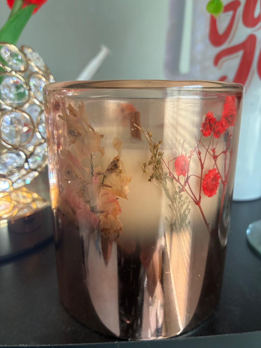Handmade pressed flower candle showing botanical detail in amber glass vessel