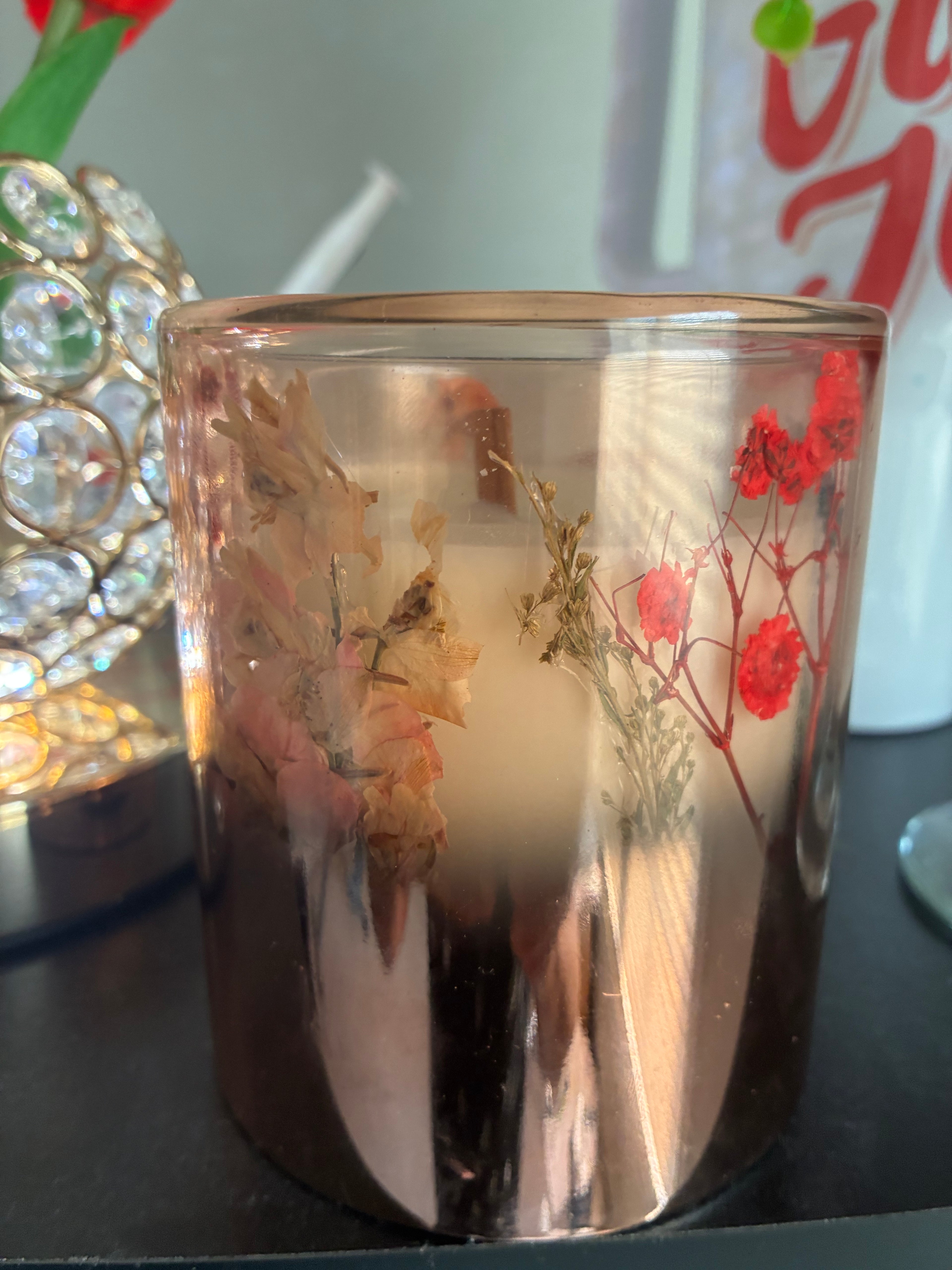 Handmade pressed flower candle showing botanical detail in amber glass vessel