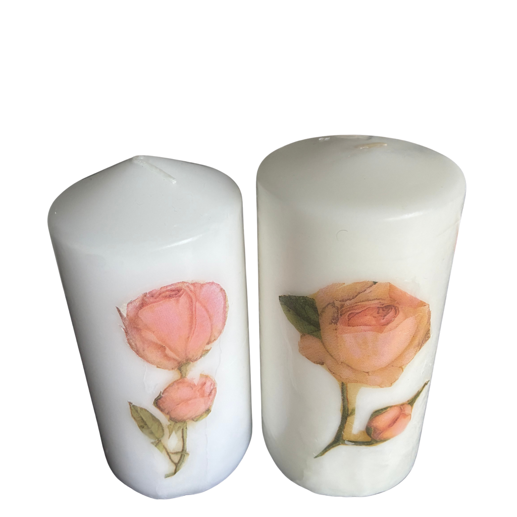 Two white pillar candles with rose botanical illustrations