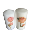 Two white pillar candles with rose botanical illustrations
