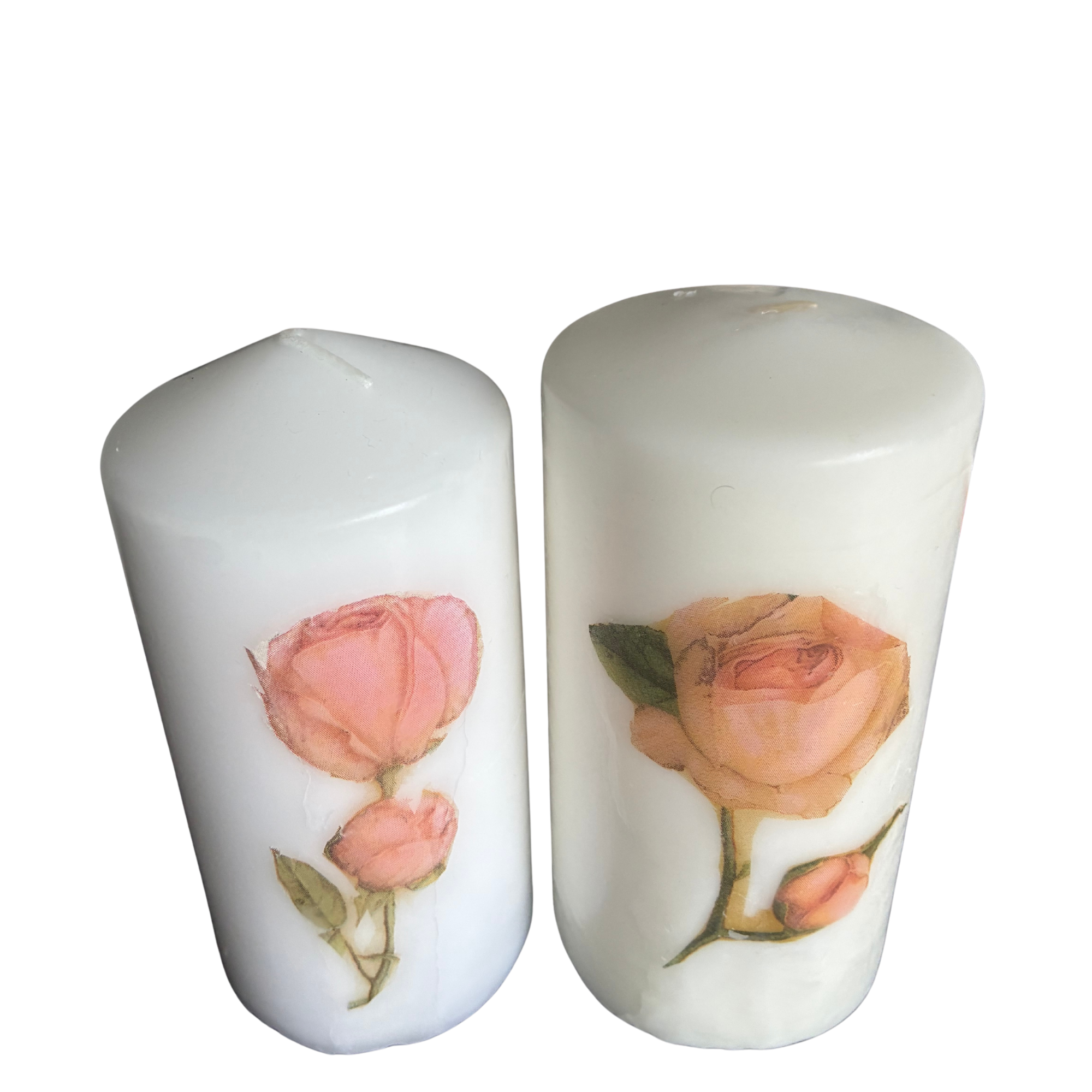Two white pillar candles with rose botanical illustrations